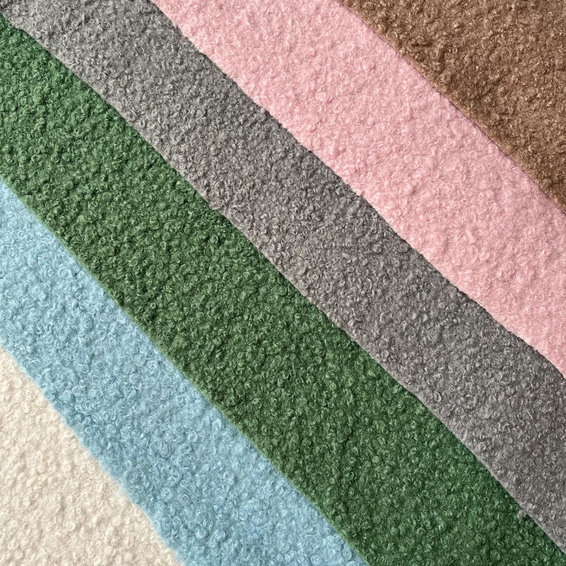 Może przedstawiać: Zbliżenie na pięć r&oacute;żnych kolor&oacute;w puszystej tkaniny. Kolory to biały, jasnoniebieski, zielony, szary i r&oacute;żowy.