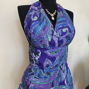 May include: A purple halter top with a paisley pattern in shades of blue, green, and pink. The top has a deep V-neckline and a fitted bodice.
