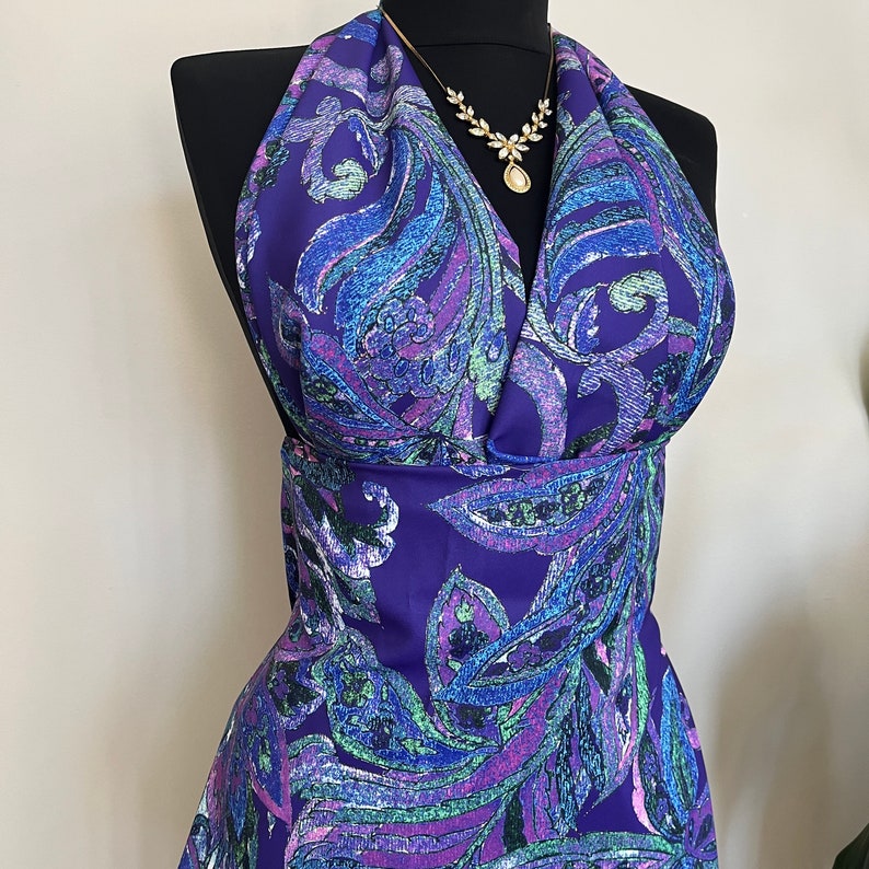 May include: A purple halter top with a paisley pattern in shades of blue, green, and pink. The top has a deep V-neckline and a fitted bodice.
