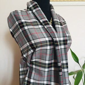 May include: Gray, white, red, and yellow plaid fabric with a black trim. The fabric is folded and draped over a black mannequin.