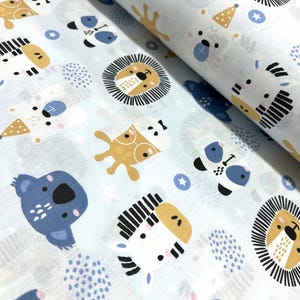 May include: A light blue fabric featuring a repeating pattern of stylized animal faces including lions, zebras, koalas, and bears. The design incorporates small white stars and blue polka dot clusters, creating a playful and repetitive graphic print.