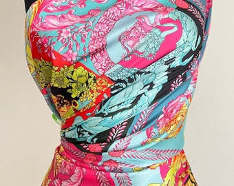 May include: A colorful fabric with a baroque pattern in shades of pink, blue, black, and gold. The fabric features intricate floral designs and ornate scrollwork.