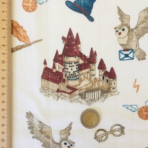 May include: White fabric with a repeating pattern of Harry Potter themed illustrations. The pattern includes Hogwarts castle, owls, a golden snitch, a wizard's hat, and a lightning bolt.