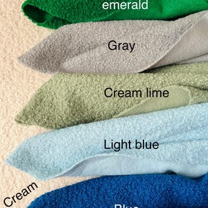 May include: A selection of fabric swatches in shades of green emerald, grey, cream lime, light blue, and blue. Each swatch is labelled with its colour. The fabric has a textured, looped appearance.