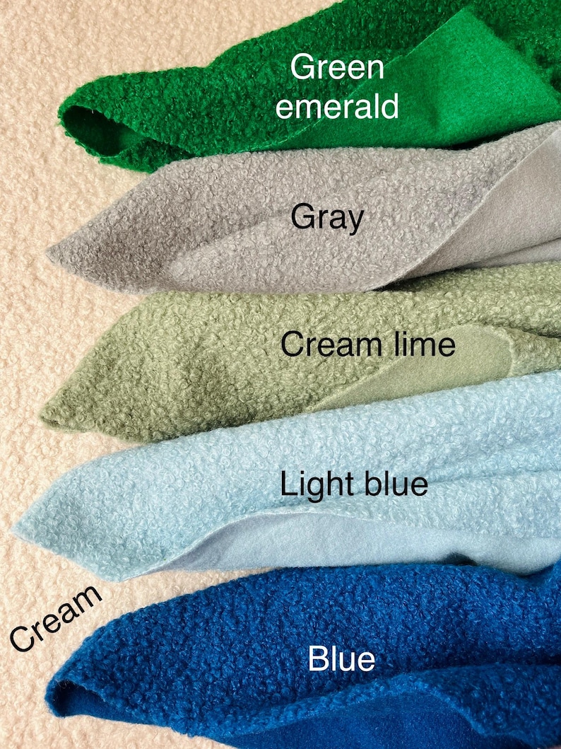 May include: A selection of fabric swatches in shades of green emerald, grey, cream lime, light blue, and blue. Each swatch is labelled with its colour. The fabric has a textured, looped appearance.