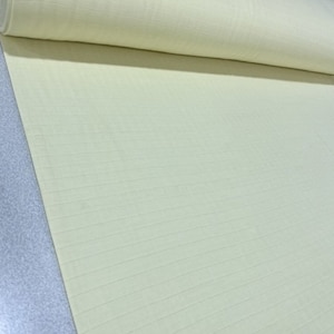 May include: A roll of pale yellow fabric featuring a subtle, grid-like texture. The material is light in color and displays a consistent, repeating pattern of thin, horizontal and vertical lines woven directly into the surface of the textile.