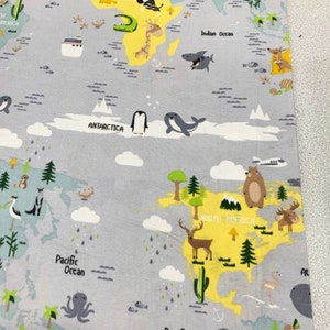 May include: A colorful fabric with a world map design. The map features continents in yellow, oceans in blue, and animals from each region. The continents are labeled with their names, such as North America, South America, and Antarctica. The fabric is perfect for crafting projects, such as quilts, pillows, and tote bags.