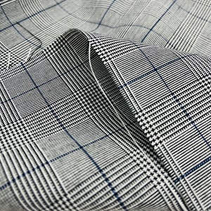 May include: Close-up of a gray and white plaid fabric with a subtle blue and black pattern. The fabric is folded and textured.