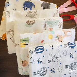 May include: Stack of six white muslin baby burp cloths with different cute animal and hot air balloon designs.