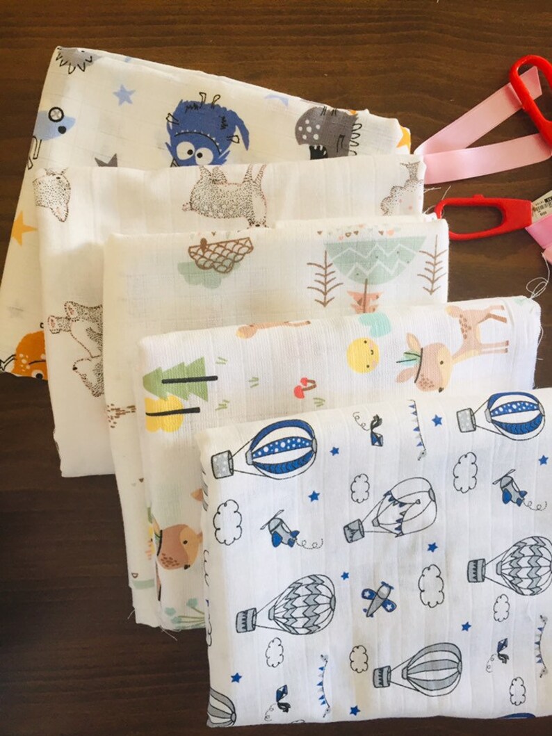 May include: Stack of six white muslin baby burp cloths with different cute animal and hot air balloon designs.
