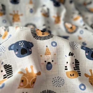 May include: White fabric with a repeating pattern of various animal faces in blue, brown, and black. The animals include a koala, a giraffe, a zebra, a lion, a panda, and a hedgehog.