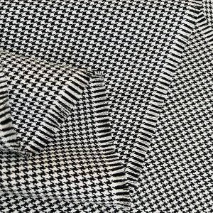 May include: Black and white houndstooth fabric with a textured weave. The fabric is folded over itself, showing the edges.