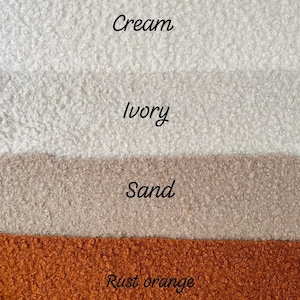 May include: Image showing four fabric samples in cream, ivory, sand, and rust orange. The colours are labelled in cursive. The fabrics have a textured, fluffy appearance, suggesting a soft, warm material.