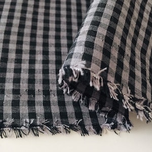 Könnte beinhalten: Schwarz-weißes Gingham-Gewebe mit ausgefranstem Rand.