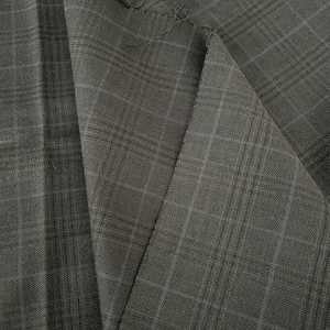 May include: Close-up of a black fabric with a subtle plaid pattern. The fabric has a woven texture and a slightly textured surface.