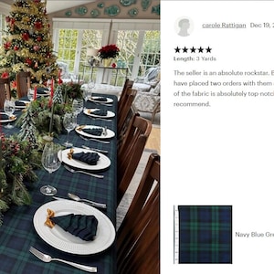 May include: A navy blue and green plaid fabric tablecloth covering a long dining table. The table is set with white plates, folded dark napkins, clear glassware, silver cutlery, and festive evergreen centerpieces with pinecones and red candles.