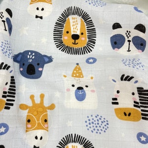 May include: A white fabric with a blue background featuring various animal illustrations. The animals include a lion, a koala, a panda, a zebra, a giraffe, and a polar bear. The fabric is decorated with small white stars and blue dots.