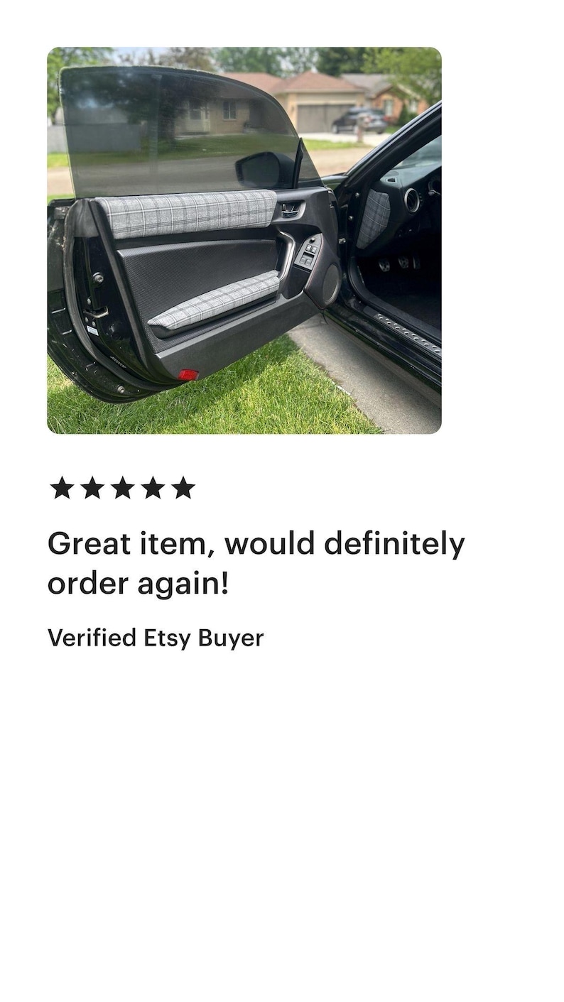 May include: A black car door interior panel featuring grey and white plaid fabric inserts on the upper door trim and the armrest. The door panel is constructed from black plastic with a smooth finish, including a handle and window controls.