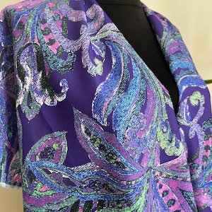 May include: Purple fabric with a paisley pattern in shades of blue, green, and pink.