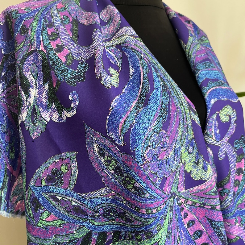 May include: Purple fabric with a paisley pattern in shades of blue, green, and pink.
