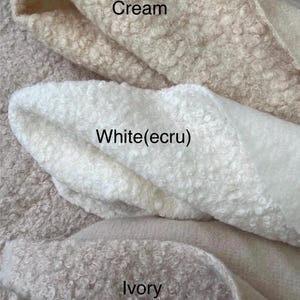 May include: Close-up of three fabric swatches in cream, white (ecru), and ivory. The fabrics have a textured, looped pile. The colours are labelled with text: "Cream", "White(ecru)", and "Ivory".