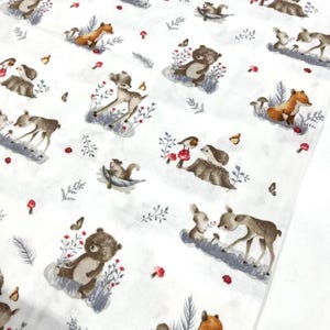 May include: White fabric with a repeating pattern of woodland animals, including deer, bears, foxes, squirrels, and rabbits. The illustrations are in soft brown and gray tones, with red mushrooms and butterflies scattered throughout.