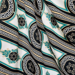 May include: Black and white fabric with a repeating pattern of teal and gold Greek key designs. The fabric has a subtle sheen and a soft texture.