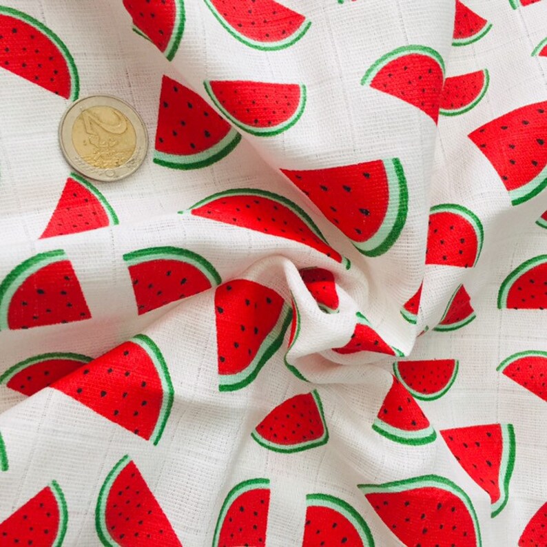 May include: White fabric with a repeating pattern of red watermelon slices with green rinds.