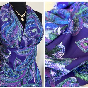 May include: Purple fabric with a paisley pattern in shades of blue, green, and pink. The fabric has a textured surface.