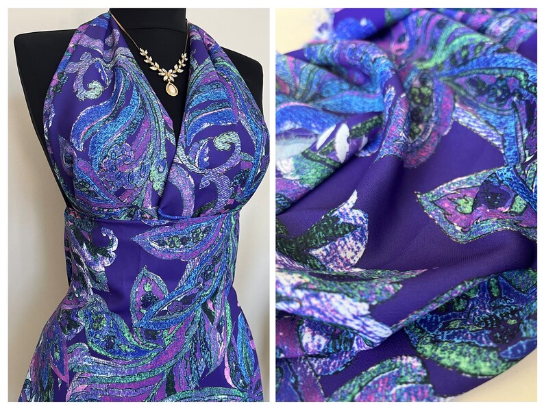 May include: Purple fabric with a paisley pattern in shades of blue, green, and pink. The fabric has a textured surface.
