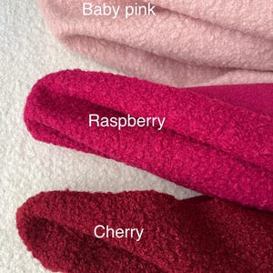 May include: Close-up of three fabric swatches in baby pink, raspberry, and cherry colours. The fabric has a textured, looped appearance. The colour names are written on the fabric.