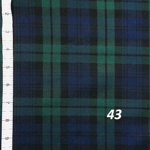 A close-up of a black, green, and blue plaid fabric. A ruler with inches and centimeters is visible on the left side of the image. The number 43 is visible in the bottom right corner of the image.