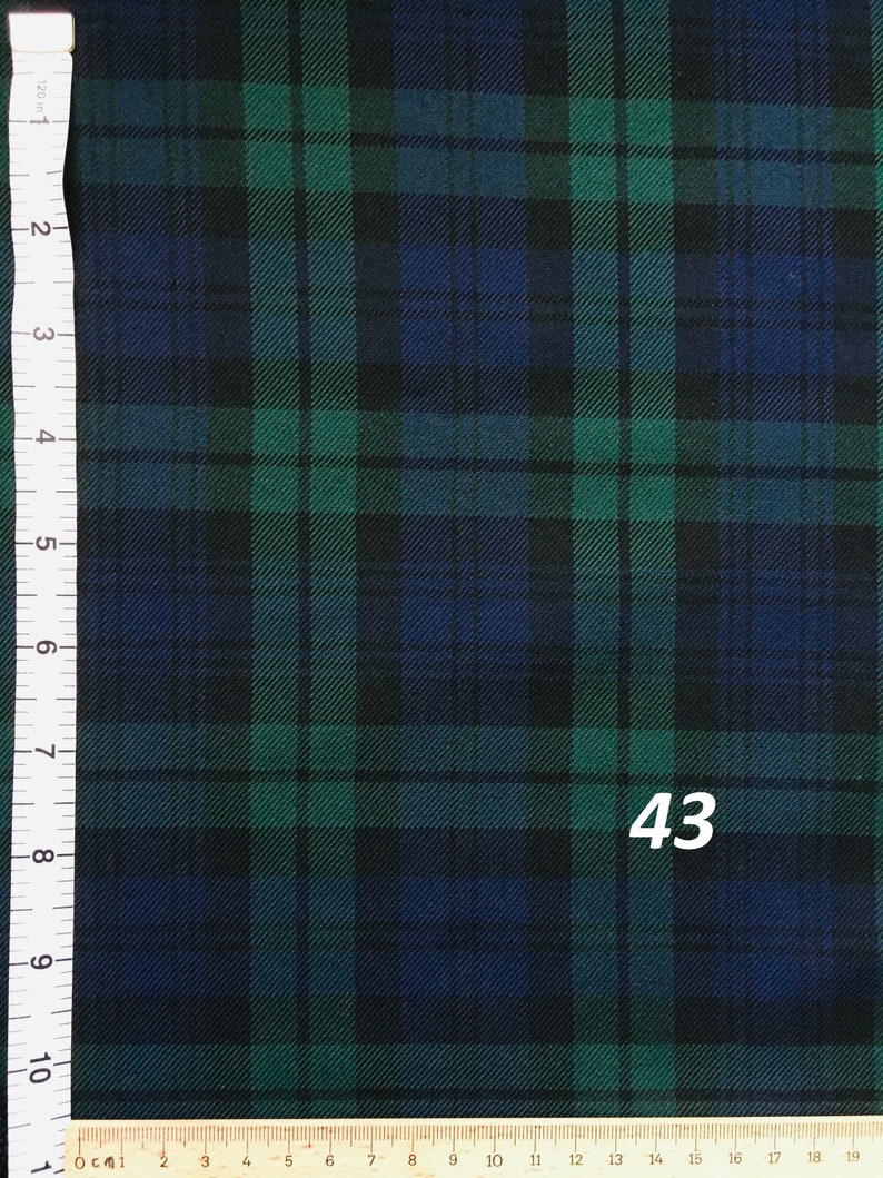 A close-up of a black, green, and blue plaid fabric. A ruler with inches and centimeters is visible on the left side of the image. The number 43 is visible in the bottom right corner of the image.