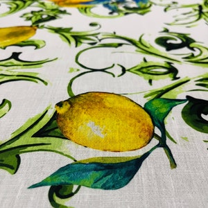 Puede incluir: Primer plano de un mantel blanco con un patr&oacute;n repetido de limones amarillos, hojas verdes y vides verdes onduladas. Los limones est&aacute;n detallados con sombreado, y las hojas tienen un efecto de acuarela. La tela tiene una textura de lino.