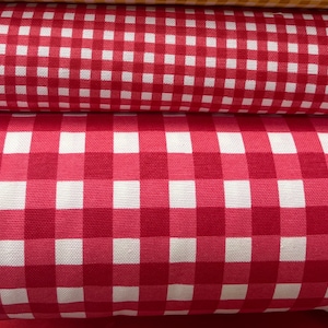 May include: Red and white gingham fabric with a checkered pattern. The fabric is folded in a stack.