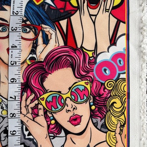 May include: Colorful fabric with a pop art design featuring three women with exaggerated features. The women are wearing sunglasses, red lipstick, and have pink, blonde, and blue hair. The fabric has a white background with black outlines and the word "WOW" in yellow letters.