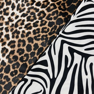 Può includere: Primo piano di due fantasie di tessuto: stampa leopardata marrone, nera e crema, e strisce zebrate bianche e nere. I tessuti sono angolati l'uno contro l'altro, mostrando i disegni contrastanti. Ideale per moda o arredamento.