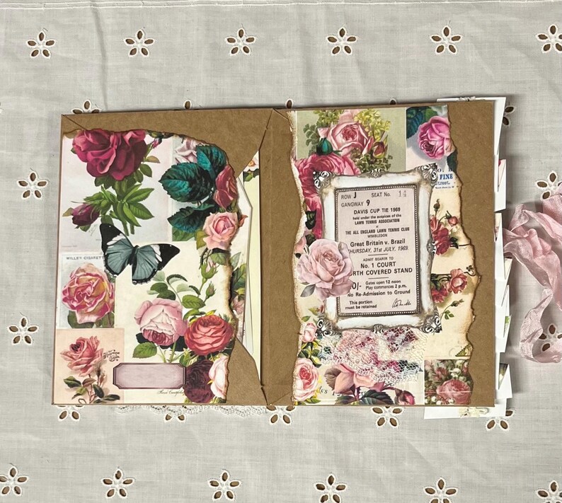 Pu&ograve; includere: Un album con copertina marrone e pagine decorate con motivi floreali, tra cui rose, farfalle e un biglietto vintage per la Coppa Davis.