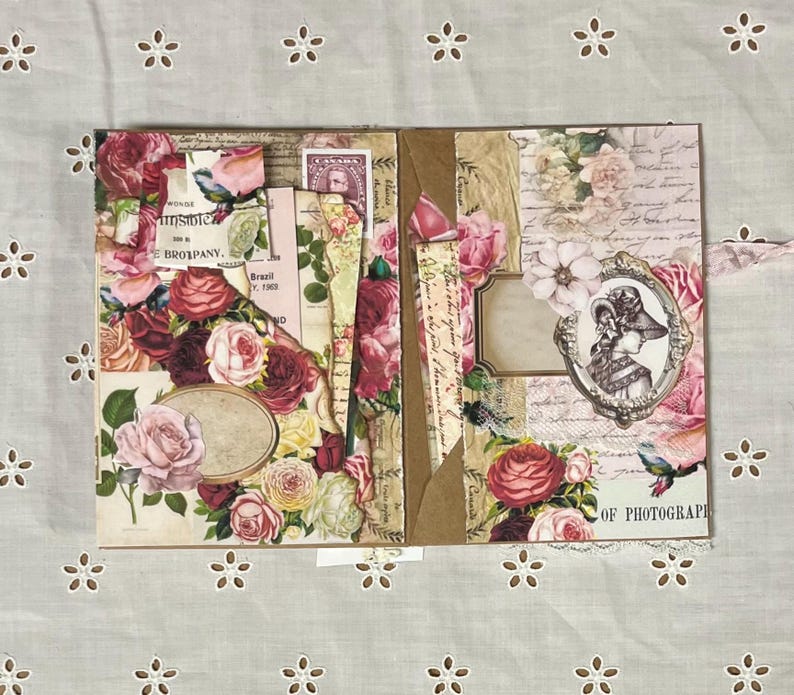 Pu&ograve; includere: Un album di scrapbooking a tema floreale. La copertina &egrave; decorata con rose rosa e rosse, foglie e altri elementi floreali. L'album &egrave; aperto per rivelare una pagina con una foto in stile vintage di una donna con un cappello. La pagina contiene anche una nota scritta a mano che dice "Of Photography".