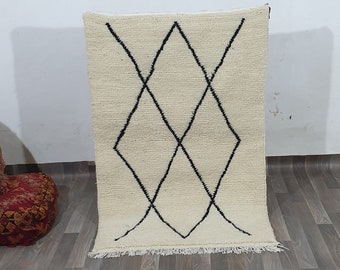 Könnte beinhalten: Ein weißer Teppich mit einem schwarzen Diamantenmuster. Der Teppich liegt auf einem Holzboden.