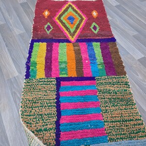May include: A colorful Moroccan rug with a geometric pattern. The rug is made of wool and has a variety of colors, including red, green, blue, and yellow.