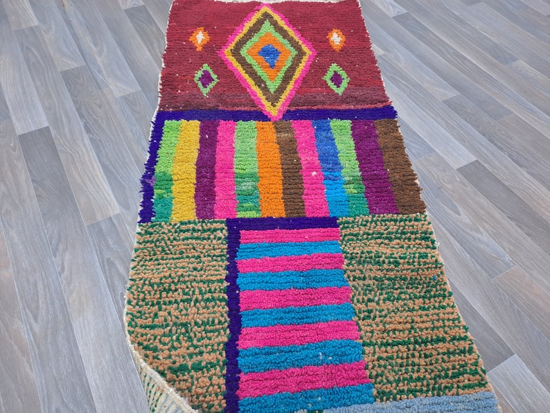 May include: A colorful Moroccan rug with a geometric pattern. The rug is made of wool and has a variety of colors, including red, green, blue, and yellow.