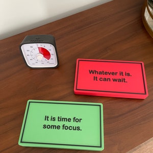 May include: Two motivational signs with black text on a colorful background. The green sign reads "It is time for some focus." The red sign reads "Whatever it is. It can wait."