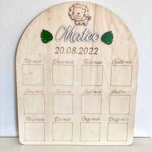 Peut inclure: Un tableau de croissance en bois avec un motif de lion et de feuilles. Le tableau comporte 12 cases pour marquer la croissance d'un enfant chaque mois. Le tableau est personnalisé avec le nom "Mateo" et la date "20.08.2022".