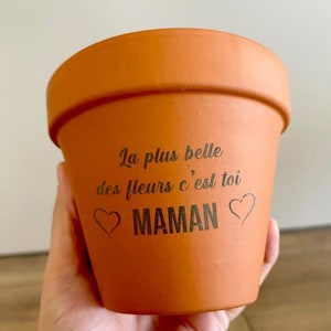 Peut inclure: Un pot de fleurs en terre cuite avec le texte "La plus belle des fleurs c'est toi" et "MAMAN" avec deux cœurs.