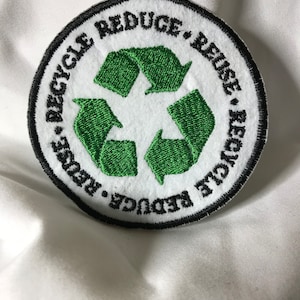 May include: A round, white patch with a black border and green recycling symbol. The text "Reduce, Reuse, Recycle" is written around the symbol.