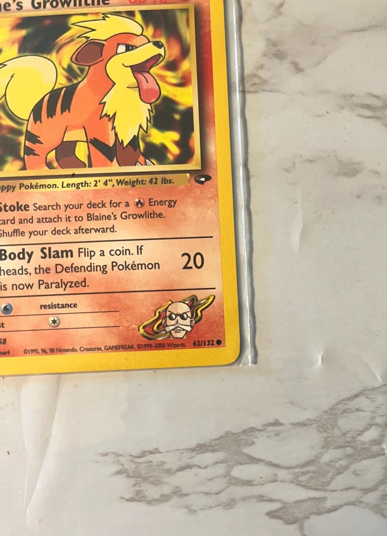 以下が含まれることがあります： オレンジと黒の犬のような生き物、ガーディのポケモンカード。カードには「Body Slam」や「Stoke」などのテキストがあります。カードの長さは71cm、重さは19kgです。