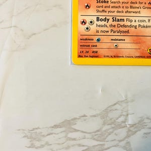 以下が含まれることがあります： アーケインのイラストが描かれたポケモンカード。カードには、「ストーク」と「ボディスラム」の攻撃の詳細、ポケモンのレベルと弱点も記載されています。カードは保護スリーブに入っています。