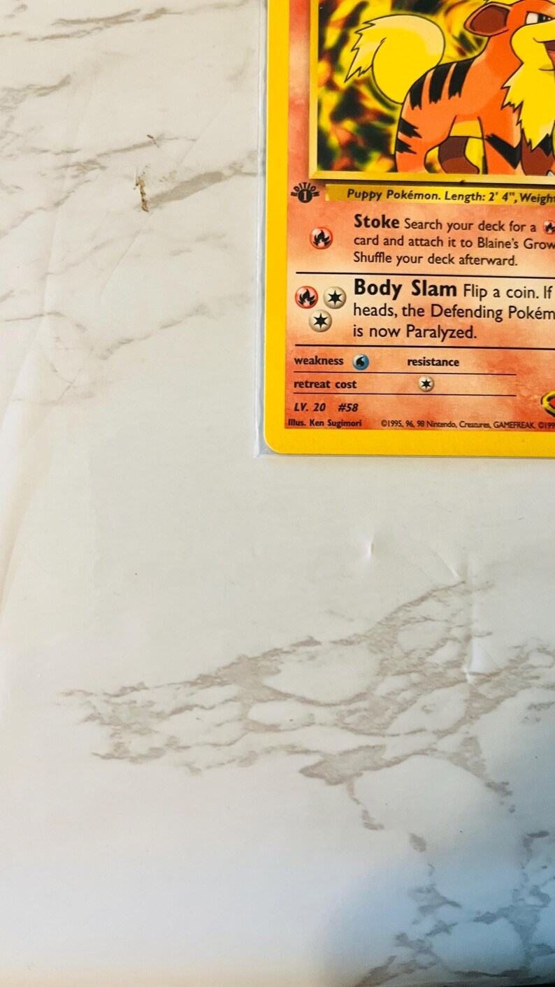 以下が含まれることがあります： アーケインのイラストが描かれたポケモンカード。カードには、「ストーク」と「ボディスラム」の攻撃の詳細、ポケモンのレベルと弱点も記載されています。カードは保護スリーブに入っています。