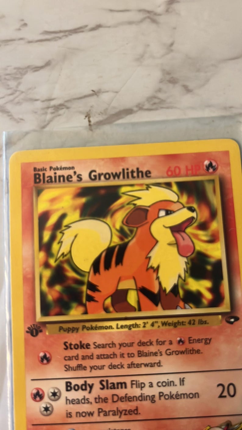 以下が含まれることがあります： Blaine's Growlitheのポケモンカード。カードは黄色の縁取りで、オレンジと黒の毛並みのGrowlitheのイラストが表示されています。テキストには「Puppy Pok&eacute;mon. 長さ：71 cm、重量：19 kg」と記載されています。